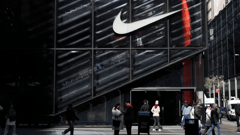 People walking outside a Nike store with a large logo in urban setting